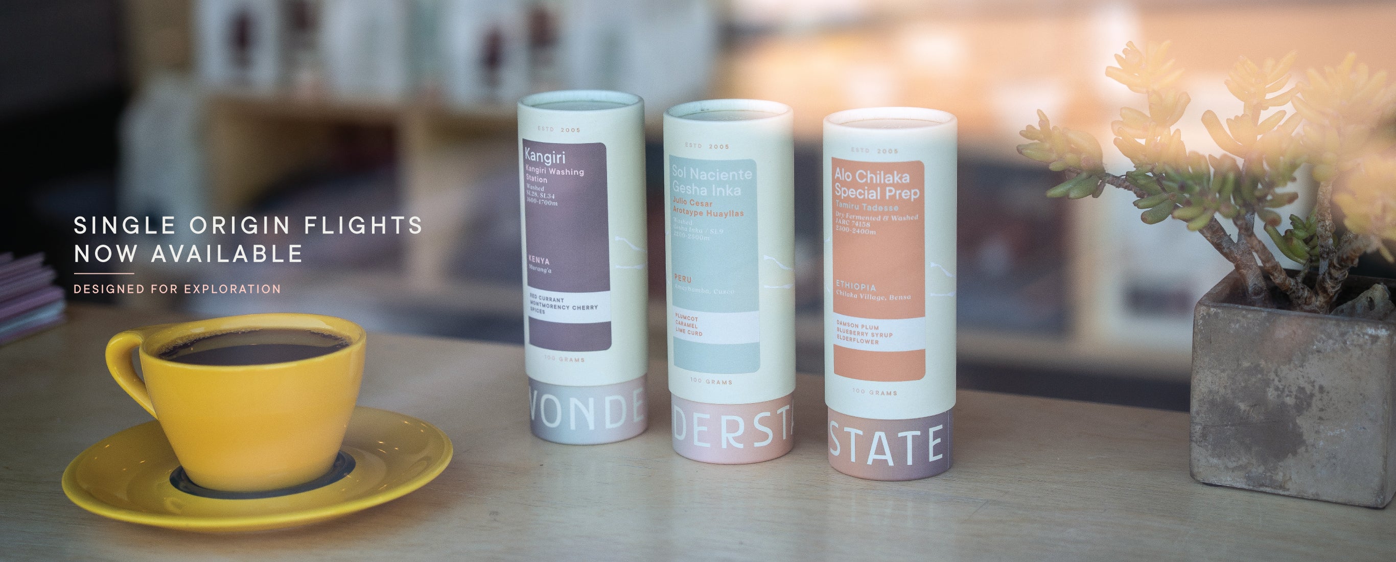 three tubes of coffee next to a yellow mug