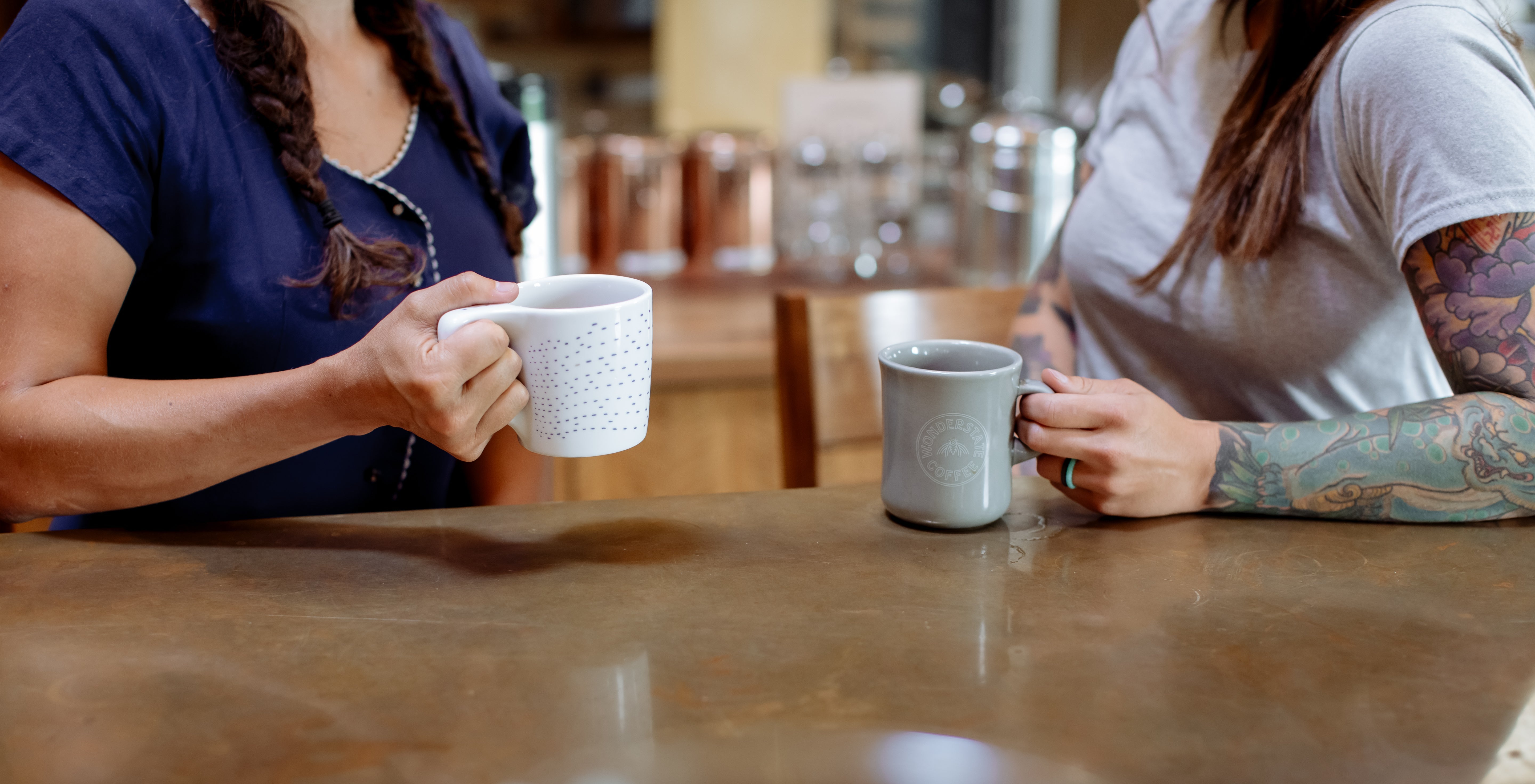 Two people sitting at a table with coffee mugs in a casual setting.