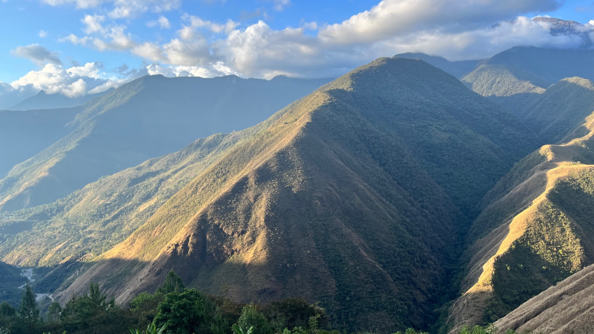 Scenic view of mountains with greenery and a blue sky.